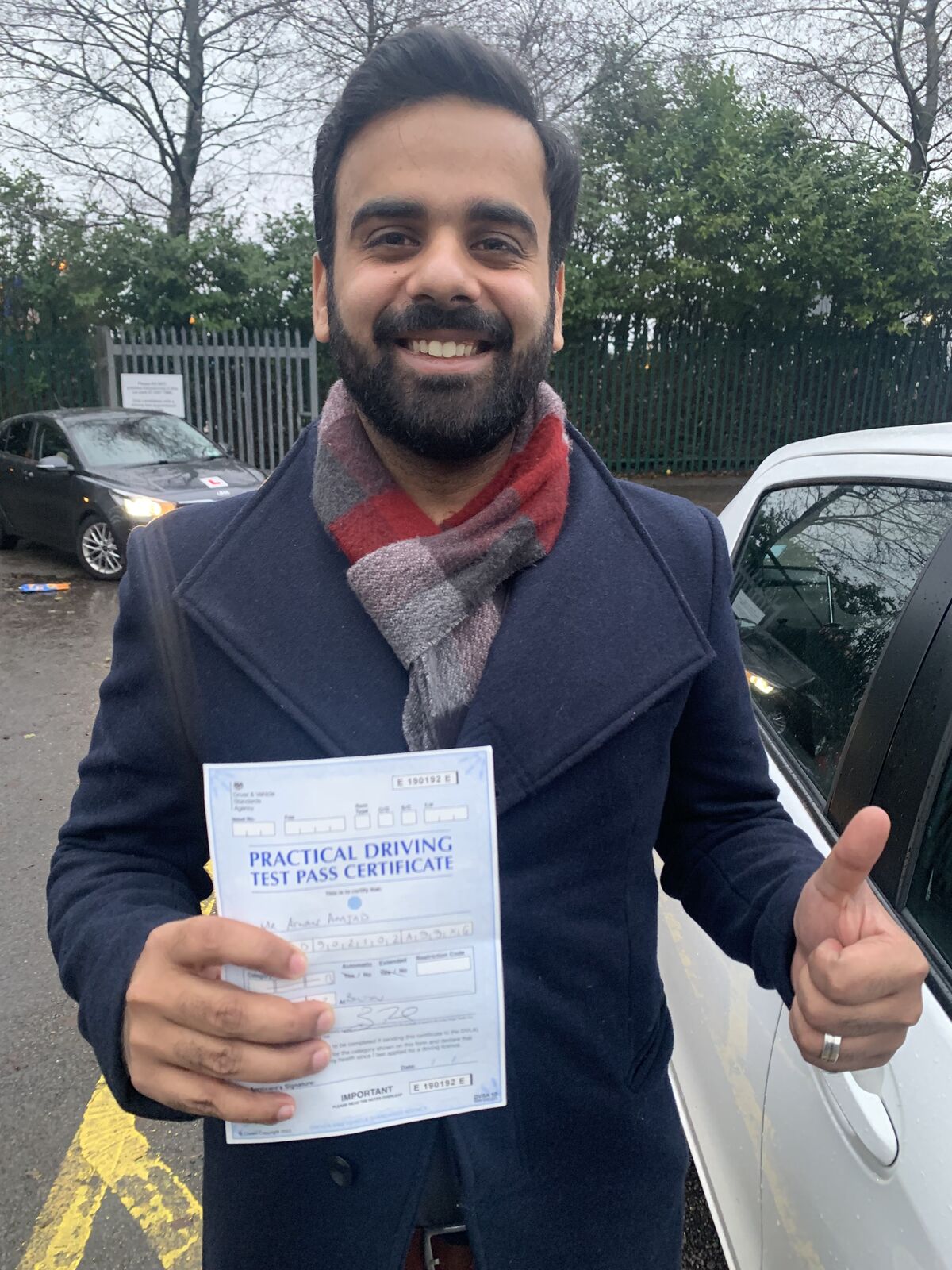 Learner smiling and holding a practical driving test pass certificate.