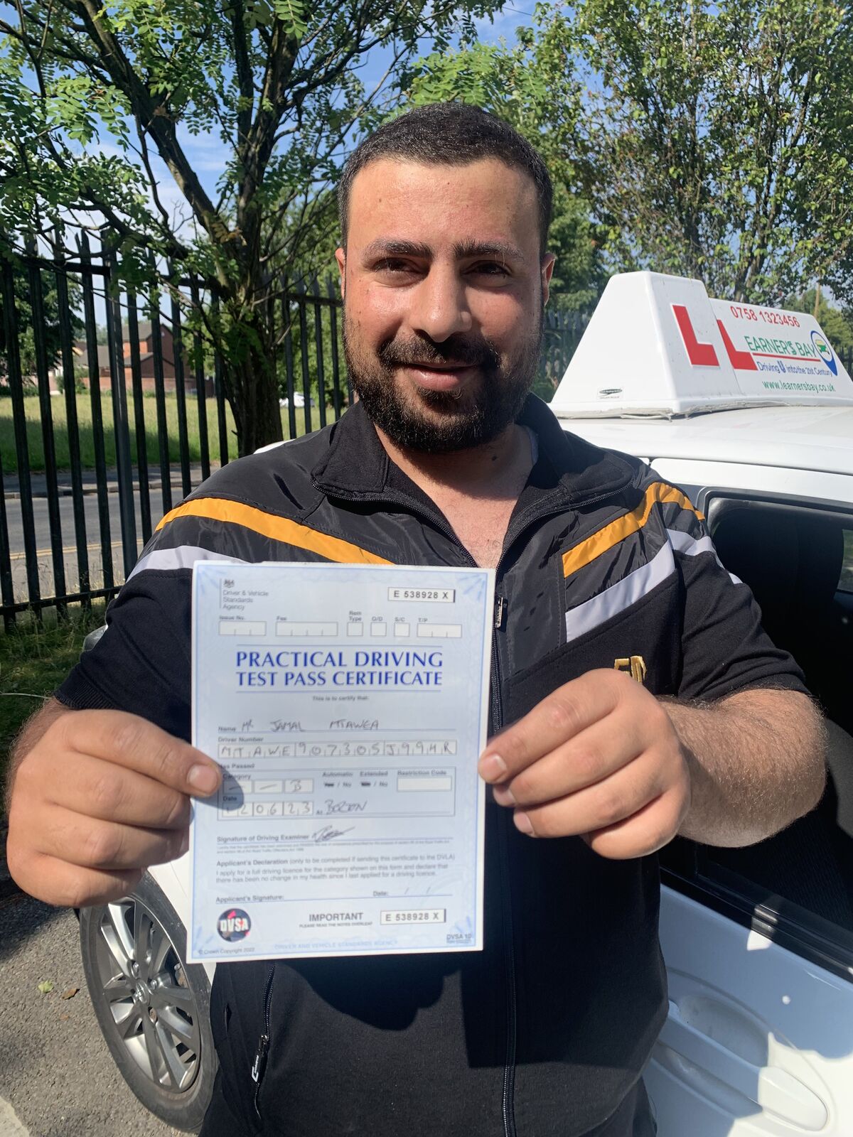 Learner smiling with their driving test pass certificate.